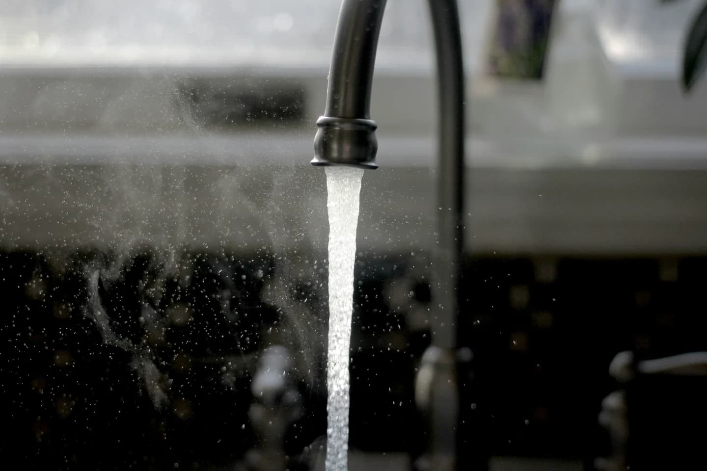 Photograph of a kitchen faucet running water into a sink